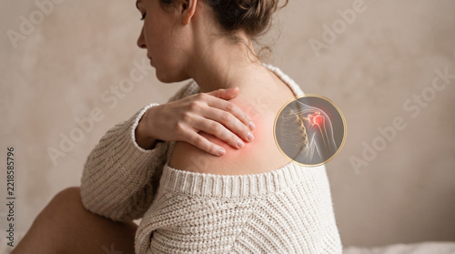 Woman in beige knit top holding painful shoulder with red glowing zone on warm neutral background. Minimal CGI rotator cuff inset. Joint pain concept
