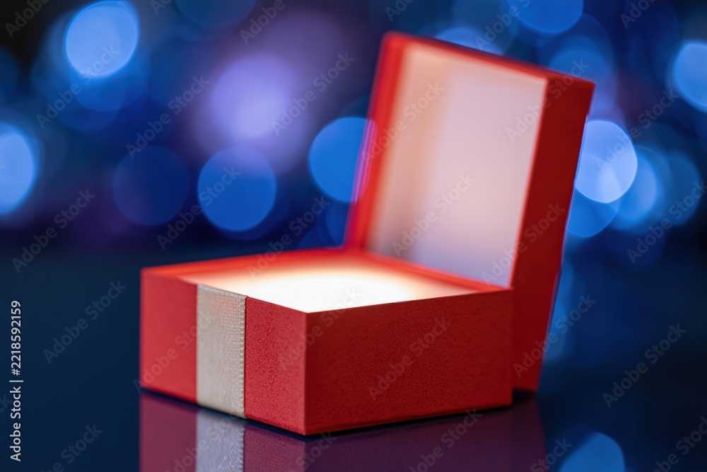 Fototapeta premium The Red Gift Box Opened Under Soft Blue Bokeh Lights