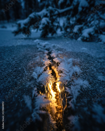 Crack in the ice with shining light and snowflakes, winter season, festive atmosphere, Christmas concept, copy space