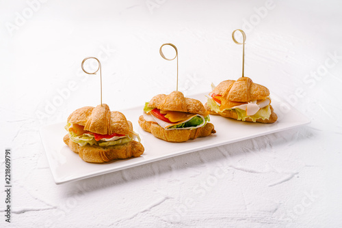 Croissant mini sandwiches filling with turkey and vegetables on white plate