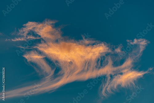 Stimmungsvoller Abend-oder Morgenhimmel mit blauem Hintergrund und von der tiefstehenden Sonnen orange angestrahlten Cirruswolken