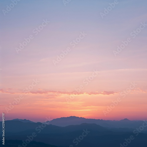 Sunset over mountain range with soft pastel sky and clouds at dusk