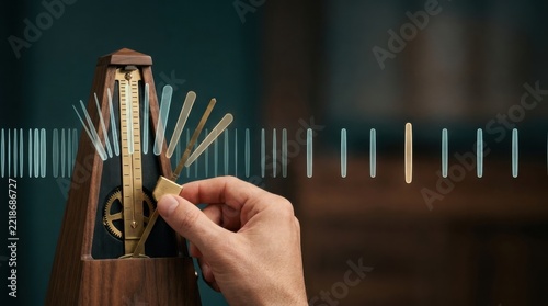 Close-up of a hand adjusting a vintage mechanical metronome with a blurred background for music practice, tempo keeping device used by musicians and students