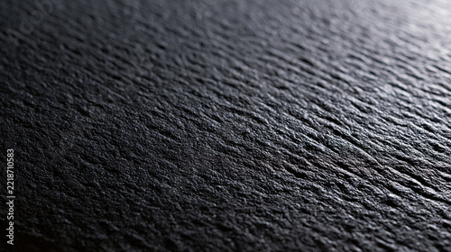 Black slate surface with fine rippled grain in shallow focus