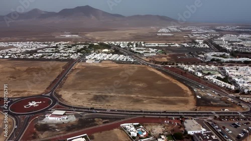 Aerial view of a coastal city with a large body of water white buildings and a road network