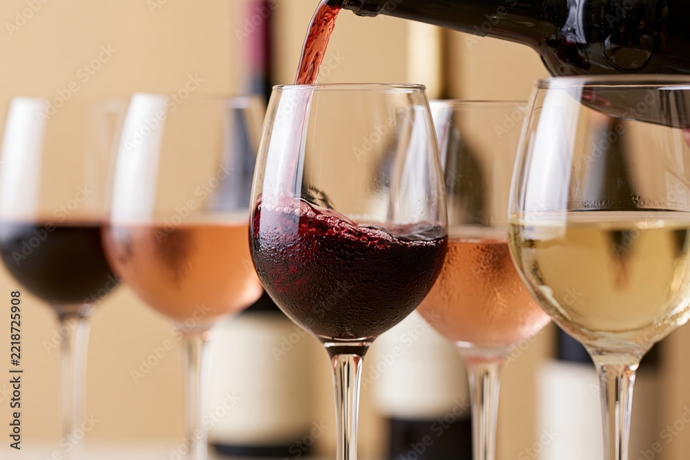 Fototapeta premium The Wine Glasses in Motion: Pouring Red and White Wine in Studio Setting