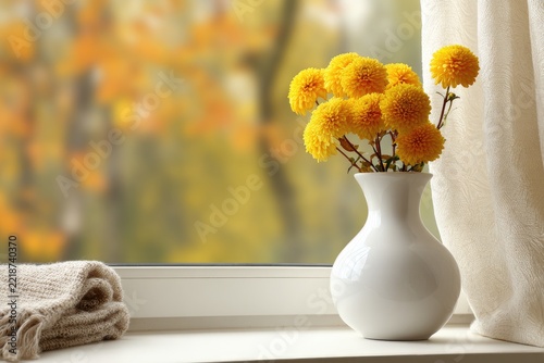 Yellow chrysanthemum bouquet in white vase on windowsill, autumnal background