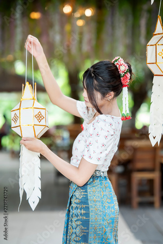Beautiful Asian woman in traditional Thai dress holding paper lantern during Lanna Loy Krathong festival.