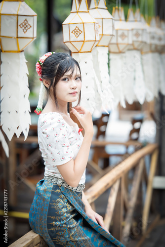 Beautiful Asian woman in traditional Thai dress holding paper lantern during Lanna Loy Krathong festival.