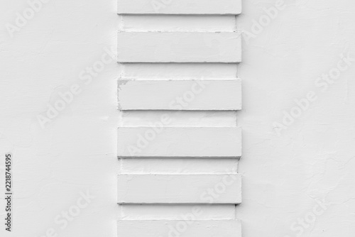 Minimal white plaster wall featuring a vertical column of rectangular reliefs, strong geometric pattern and subtle shadows. Clean architectural seamlestexture for backgrounds and design projects