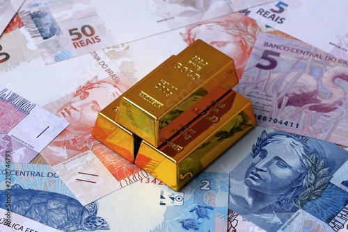 Brazilian real money bills and gold bullion bars. Brazil cash bills of BRL currency close up