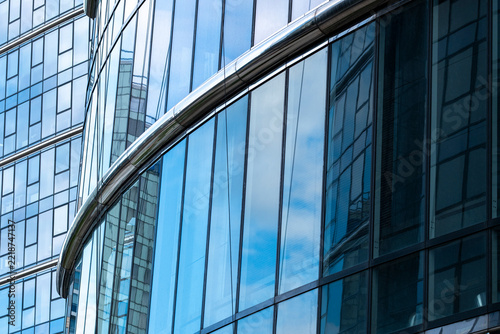 Blue reflective glass facade with a curved edge creates abstract architecture where transparency and lines follow the curved edge across the blue glass facade