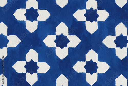 A blue and white ikat fabric with a diamond pattern. the fabric has a design with a blue white and black colors. the diamond pattern is intricate and detailed creating a and eyecatching look.
