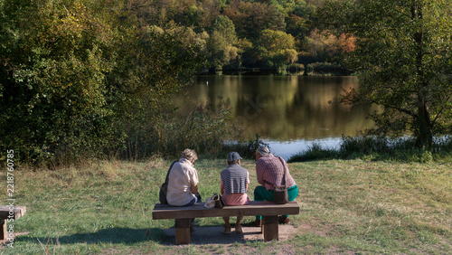 trio de personnes assis sur le banc prés de l'eau