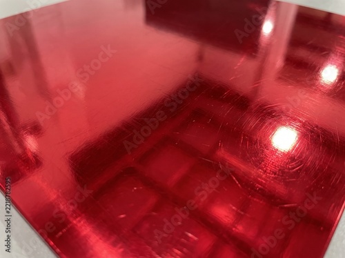 Shiny Red Metallic Surface with Reflections and Scratches.
