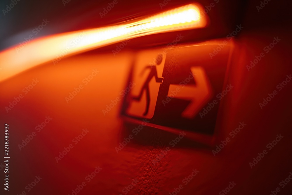 Fototapeta premium The Emergency Exit Sign Illuminated in Red Ambient Lighting with Dynamic Blur