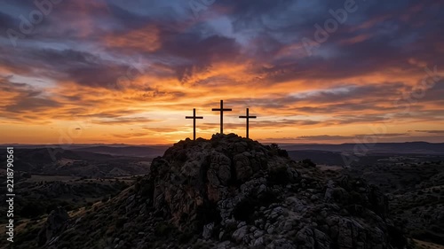 Three wooden crosses silhouetted on a hill at dramatic sunset