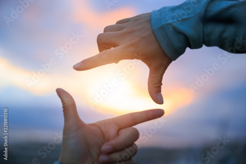 Hands making a picture frame on the sunset seaside