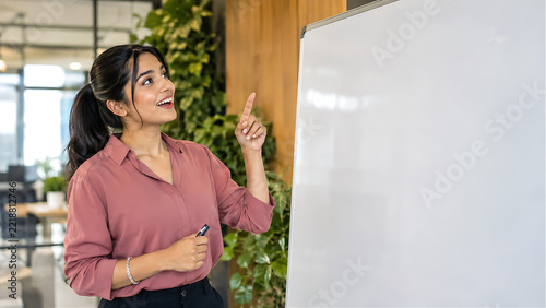 Excited businesswoman with finger raised at blank whiteboard — bright idea moment, inspiration at work