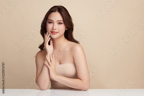 A beautiful young Asian woman with clean, fresh skin against a beige background. Skincare, facial treatment, cosmetology, beauty, and spa. An elegant portrait of an Asian woman.