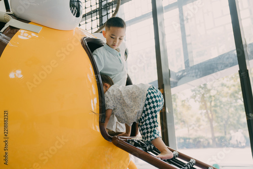 An Asian girl and her brother are playing in an indoor amusement park; an Asian family is enjoying a relaxing vacation