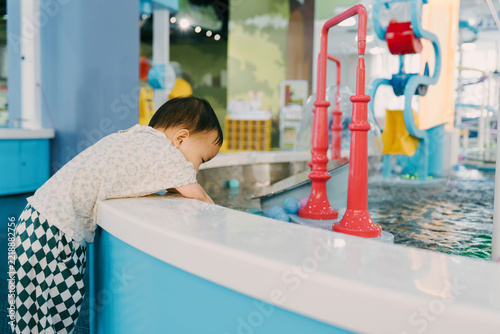 An Asian girl is playing with a water gun in an indoor amusement park; Asian families are enjoying a relaxing family trip