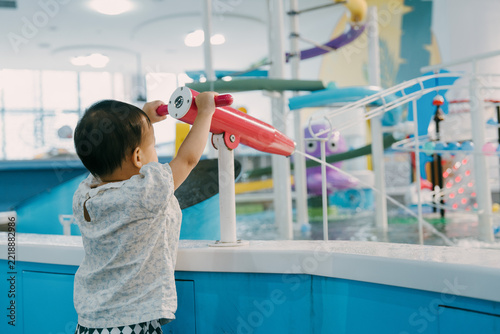 An Asian girl is playing with a water gun in an indoor amusement park; Asian families are enjoying a relaxing family trip