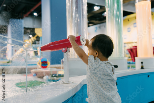 An Asian girl is playing with a water gun in an indoor amusement park; Asian families are enjoying a relaxing family trip