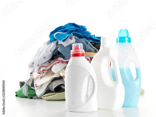 Pile of colorful clothes with multiple laundry detergent bottles against white background.
