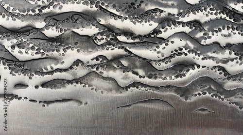 Close-up of the forged steel texture on a knife blade with a raised dark pattern.