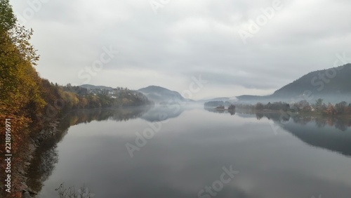 Morning mist over a river with hills in the background during autumn