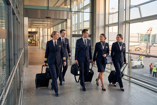 Airline flight crew walking through airport terminal with luggage before departure