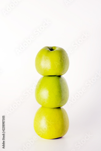 Three green apples stacked vertically on a white background. Fresh fruit and balanced healthy nutrition concept.