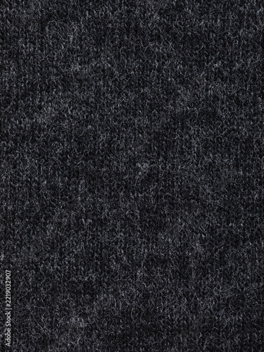 Macro texture of fluffy anthracite wool knit fabric, dark textile background filling full frame
