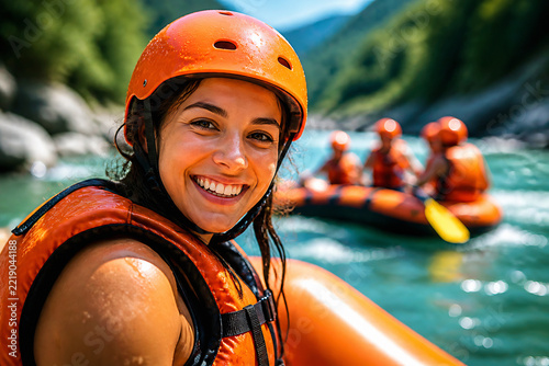 A smiling woman in an orange helmet and life vest is enjoying whitewater rafting on a river surrounded by green mountains.