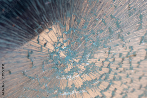 An abstract close-up of a fractured, glass-like surface forms a pale blue and beige radial pattern, drawing the eye toward a dense, starburst-shaped center