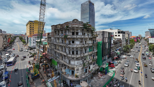 Aerial view of the demolition of an iconic modernist building, featuring a large construction crane and heavy machinery amidst a busy urban street scene in Phnom Penh, Phnom Penh, Cambodia.