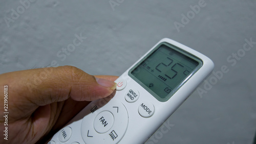 Air Conditioner Remote Control: A close-up shot shows a person's hand holding a white air conditioner remote control, with the digital display showing the temperature set at 25 degrees Celsius.