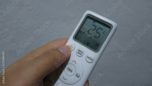 Air Conditioner Remote Control Display: A hand holds a white air conditioner remote control.