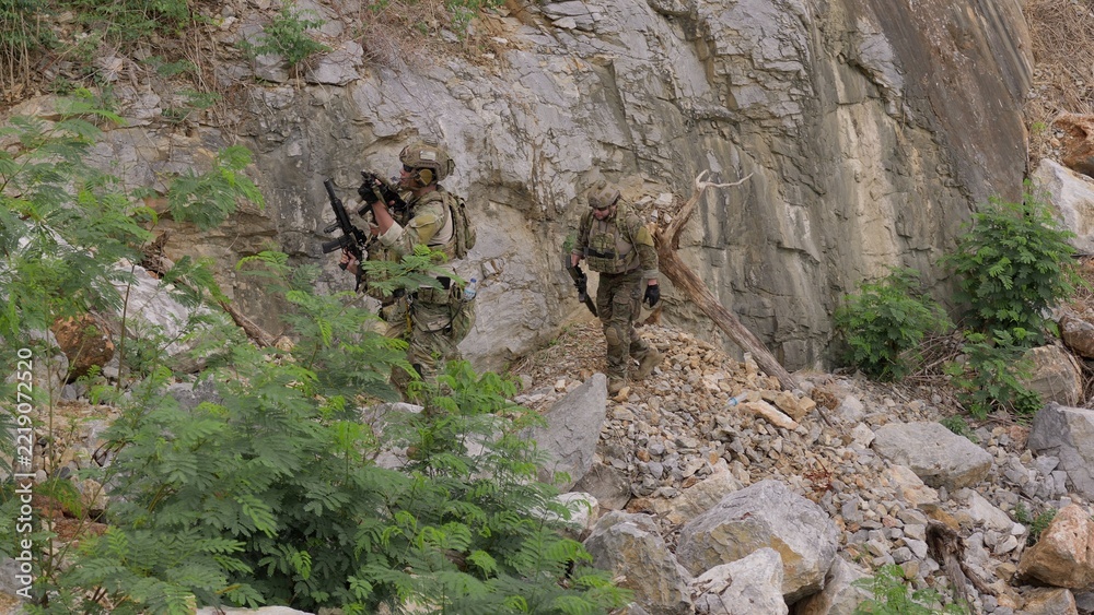 Fototapeta premium Special forces soldiers patrol through treacherous, rocky terrain during a clandestine mission, showcasing teamwork and military strategy in a hostile environment.