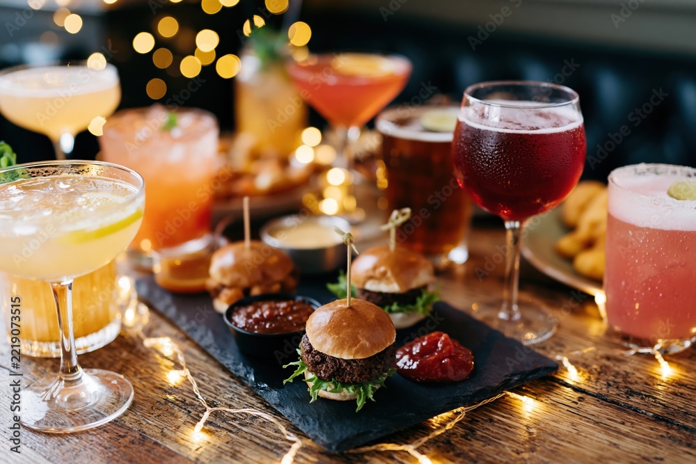 Fototapeta premium The Festive Spread of Cocktails and Sliders on a Warm Wooden Table