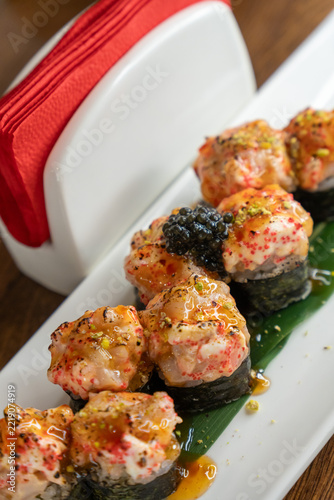 Close-up of delicious sushi rolls with seafood topping, caviar, and sauce