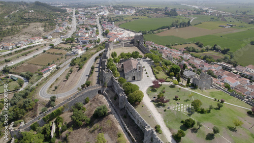 Aerial view of Montemor-o-Velho Castle with its stone walls, towers, and central church, overlooking the town and surrounding green fields in Montemor-o-Velho, Coimbra District, Portugal.