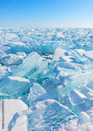 Transparent ice on Baikal lake at sunrise. Blue ice with snow against the blue sky. Baikal, Siberia, Russia.