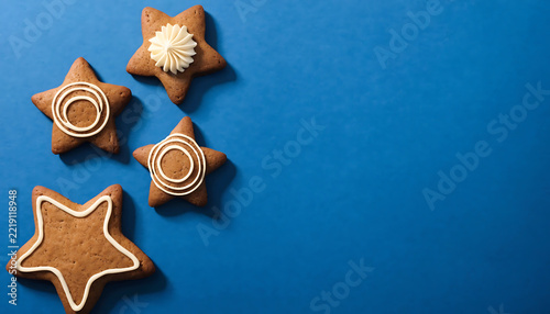 Four gingerbread star cookies with icing decorations on blue