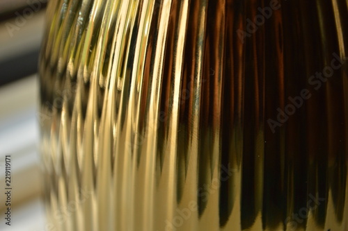 Close up view of a shiny gold metallic surface with vertical ribbed texture and soft reflections