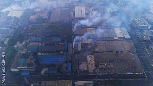 Aerial view of the industrial complex in Sachin with factory buildings and smokestacks emitting smoke in Surat, Gujarat, India.