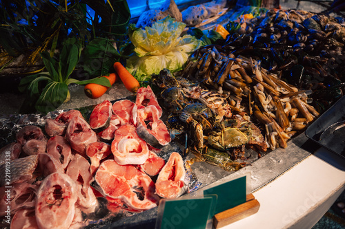 Fresh fish, shellfish, crabs, vegetables, and seafood displayed on ice at a colorful local market for cooking and culinary shopping.