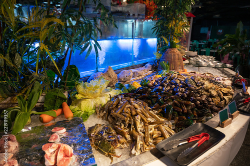 Fresh fish, shellfish, crabs, vegetables, and seafood displayed on ice at a colorful local market for cooking and culinary shopping.