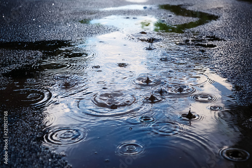 In eine Pfütze auf der Straße fallen Regentropfen